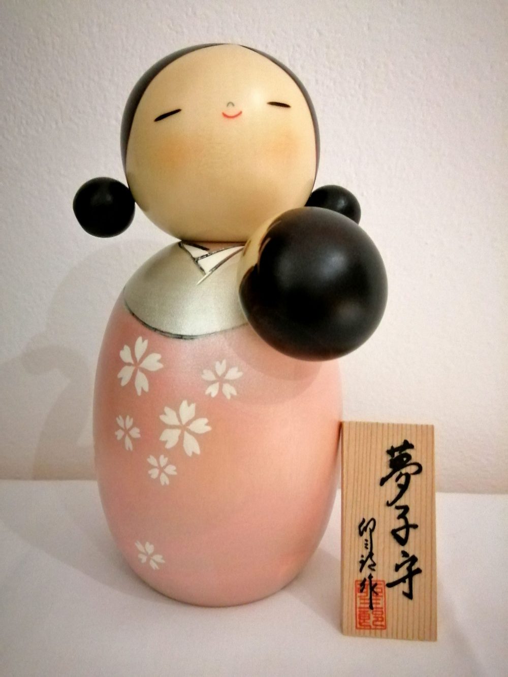 Kokeshi maternità, nome originale Yumekomori. Rappresenta una madre che culla il proprio bambino per farlo dormire in modo sereno e felice, dipinta a mano su legno.