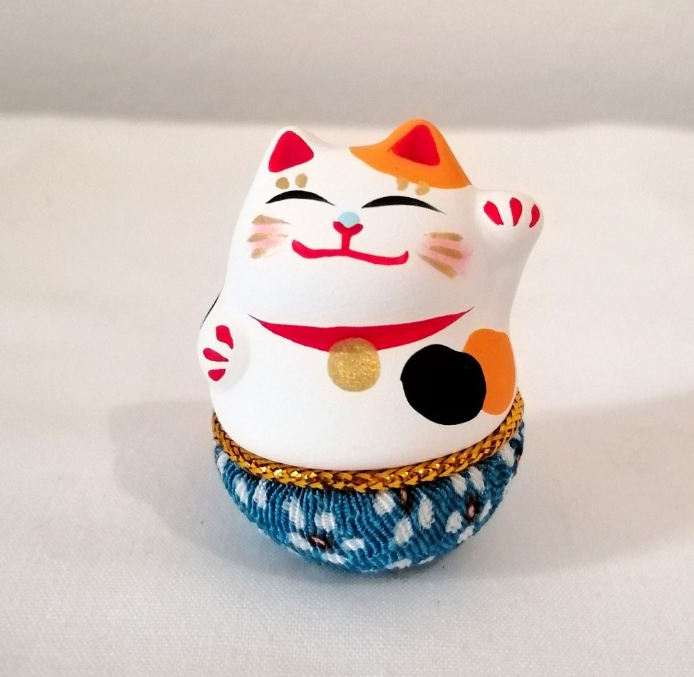 Maneki neko, gatto porta fortuna, di colore bianco con base tonda che torna sempre in piedi.