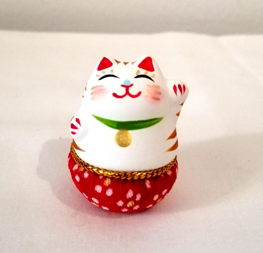 Maneki neko, gatto porta fortuna, di colore bianco e base tonda che torna sempre in piedi.