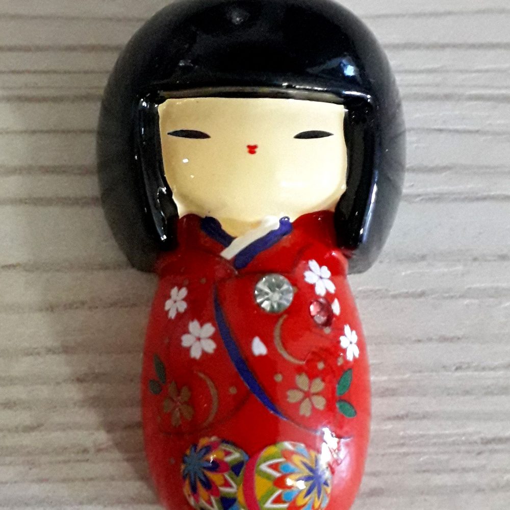 Calamita kokeshi con kimono rosso.