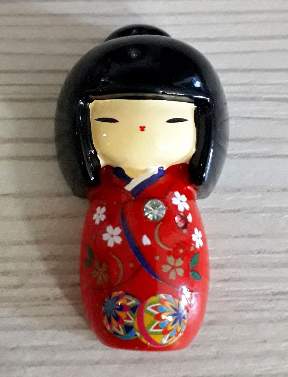 Calamita kokeshi con kimono rosso.