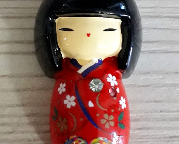 Calamita kokeshi con kimono rosso.