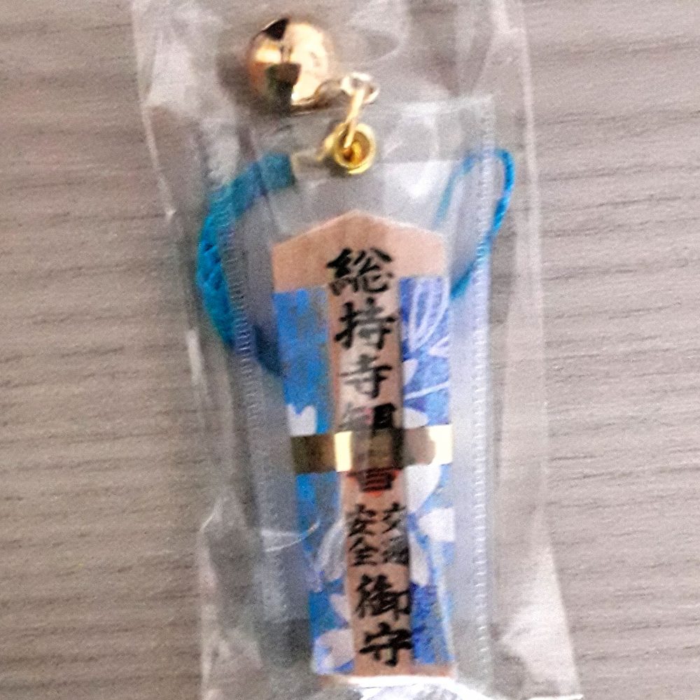 Omamori a ciondolo in legno, rivestito con stoffa di colore azzurro, per la sicurezza stradale.