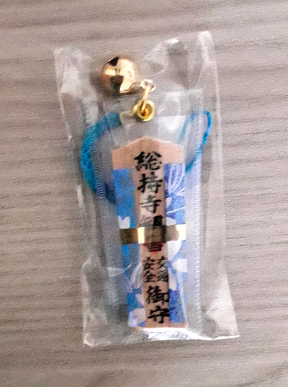 Omamori a ciondolo in legno, rivestito con stoffa di colore azzurro, per la sicurezza stradale.