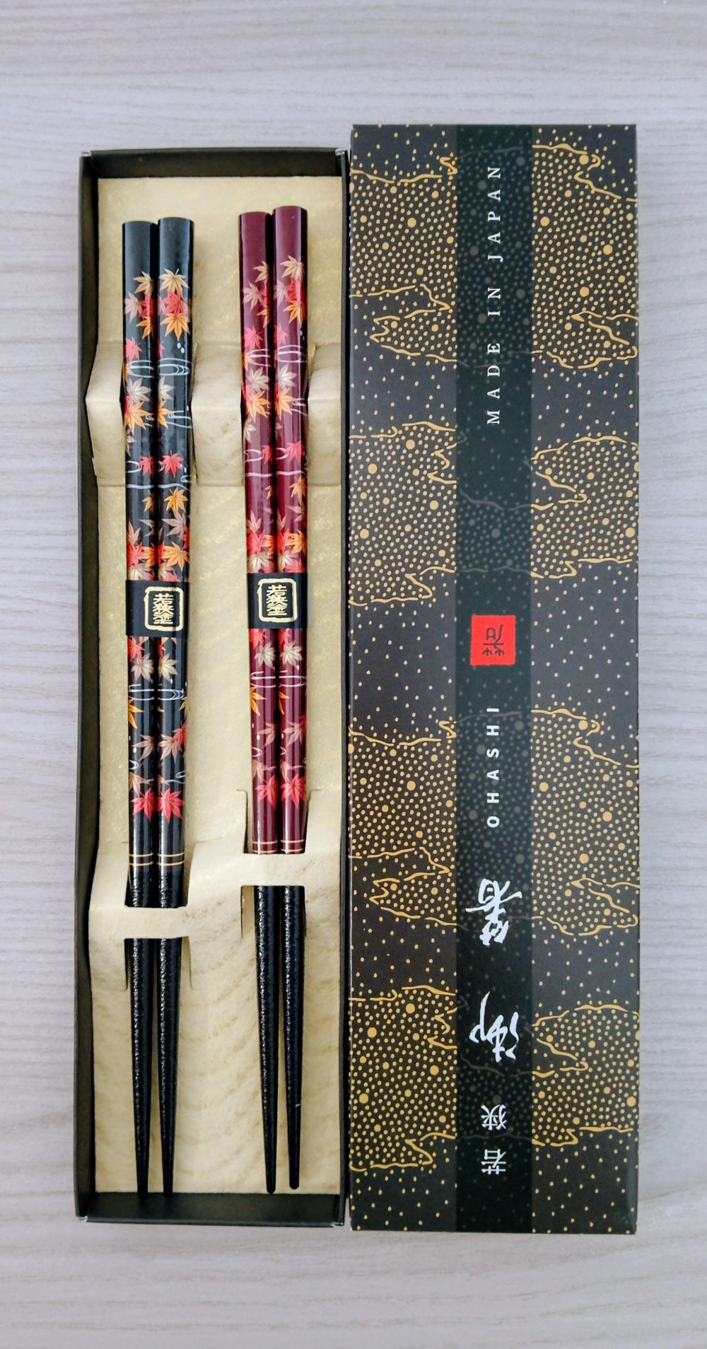 Seghettate in punta per una migliore presa del cibo. Adatte a chi è esperto e a chi si approccia a mangiare con le tipiche hashi giapponesi. Disegno di momiji, foglie di acero con i colori autunnali, una nera e una marrone, eleganti all'interno di una scatola raffinata.