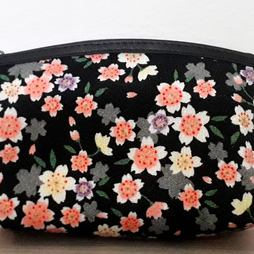 Pochette fiori bianchi e rosa su sfondo nero. Apertura con una comoda zip, può essere usata come porta trucchi, come pochette per una serata speciale, o anche da tutti i giorni, o come porta oggetti all'interno della borsa. Un oggetto davvero versatile e bellissimo, proveniente da Kyoto.