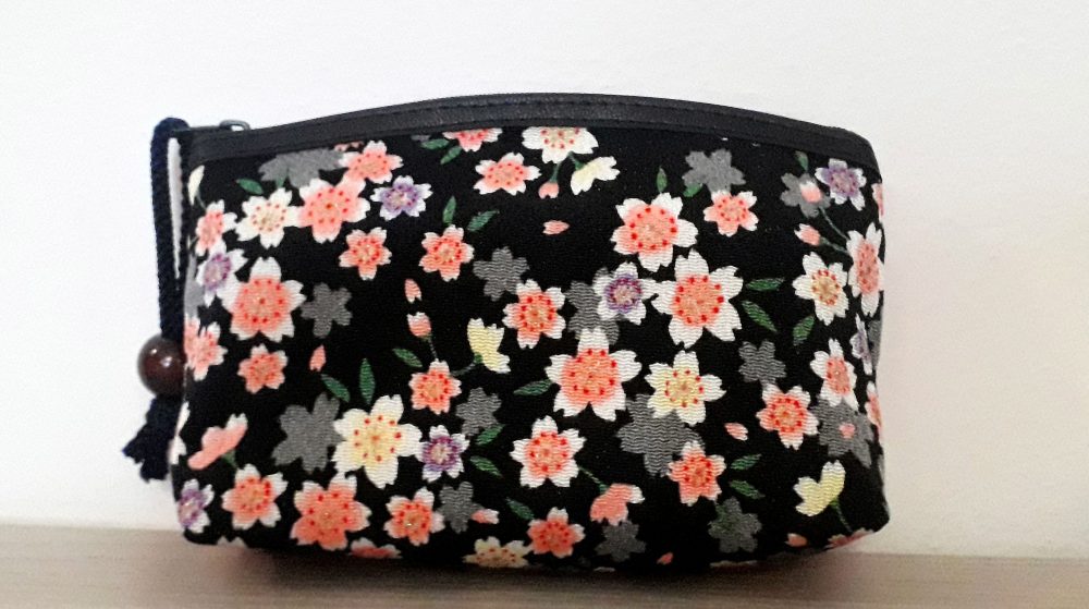 Pochette fiori bianchi e rosa su sfondo nero. Apertura con una comoda zip, può essere usata come porta trucchi, come pochette per una serata speciale, o anche da tutti i giorni, o come porta oggetti all'interno della borsa. Un oggetto davvero versatile e bellissimo, proveniente da Kyoto.
