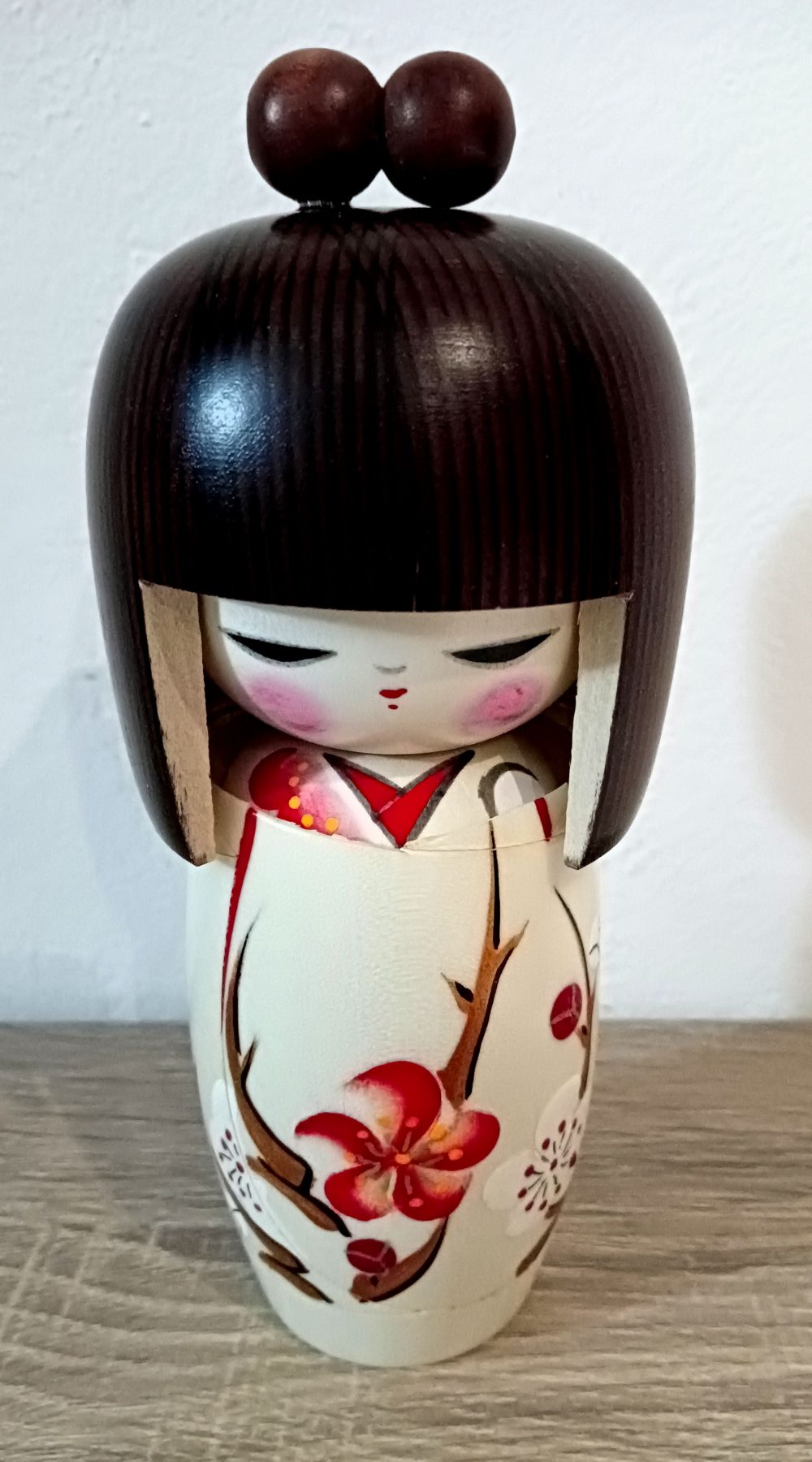 Questa è una Kokeshi Shingata, ovvero creativa, hanno il busto più corto di quelle tradizionali e più arrotondato, con colori e motivi più moderni. Hanno il busto più corto di quelle tradizionali e più arrotondato, con colori e motivi più moderni. Il nome originale di questa kokeshi è "Haru no yume", ovvero sogno di primavera. Sul kimono bellissimi fiori primaverili, capelli castani e codini. Molto bella dai colori tenui, ed un volto che trasmette serenità.