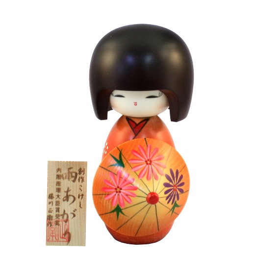Il nome di questa kokeshi è Ameagari che significa "dopo la pioggia". Di colore arancione con un kimono di un arancione sgargiante e decorazioni di fiori. Tiene un ombrello aperto in mano anch'esso arancione e fiorato. L'ombrello nella cultura giapponese è considerato un porta fortuna, l'attesa del sole dopo la pioggia.